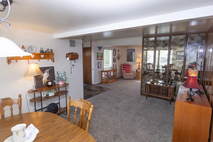 Open-concept living space with carpeted flooring and an expansive mirrored wall