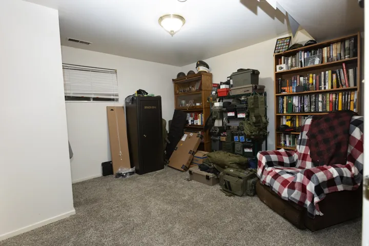 Carpeted room with a ceiling-mounted light fixture, a window with horizontal blinds, and white walls