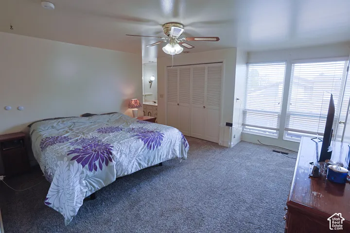 Carpeted flooring, ceiling fan with integrated lighting, multiple windows with blinds, and bi-fold closet doors