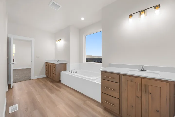 Dual wood-finish vanities with undermount sinks and light-toned countertops