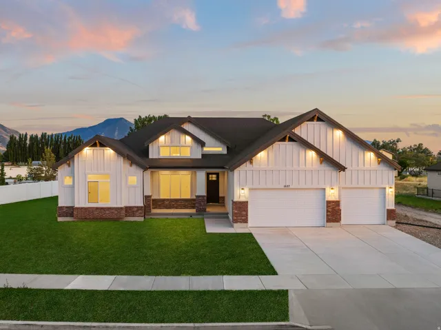 Modern farmhouse-style exterior featuring board and batten siding, brick accents, a dark roof, and an attached three-car garage
