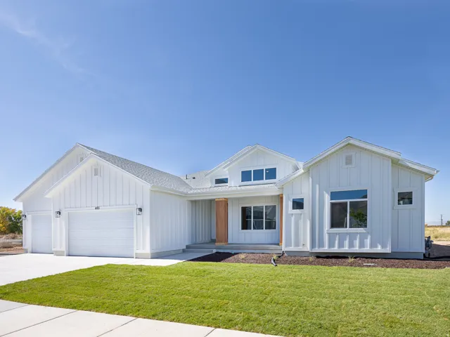 Contemporary farmhouse exterior featuring white board and batten siding, multiple gables, and a two-car garage