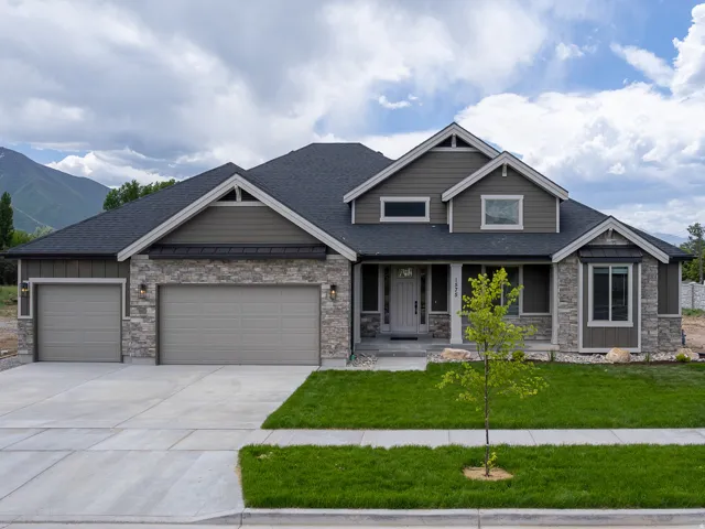 Stone and siding exterior with a dark-pitched roof, featuring a two-car garage, a single-car garage, and a concrete driveway