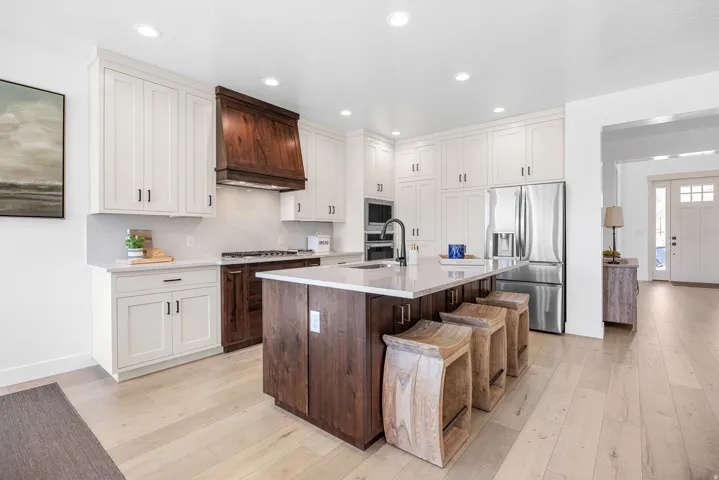 Two-tone cabinetry with a dark wood-finish kitchen island and a light wood-finish floor