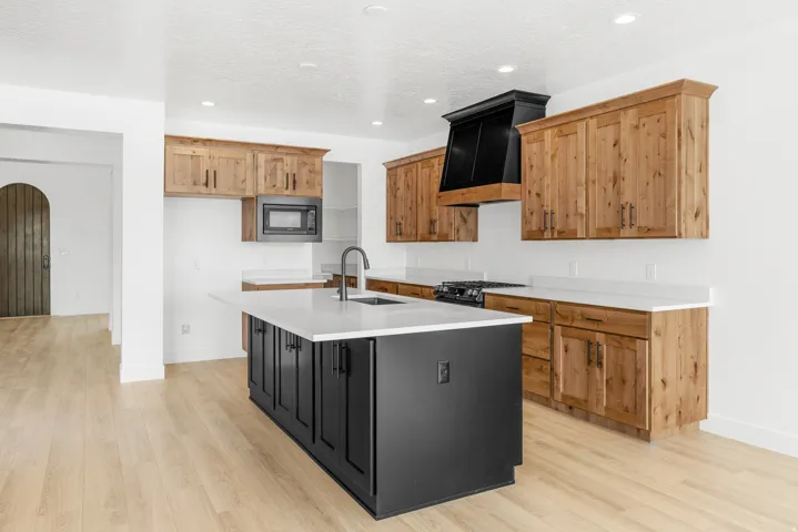 Open-concept kitchen with light wood-finish flooring, white walls, and recessed lighting