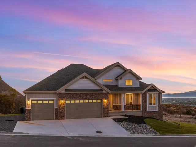 Crafted exterior featuring stone and siding finishes, an attached three-car garage, and a covered front porch