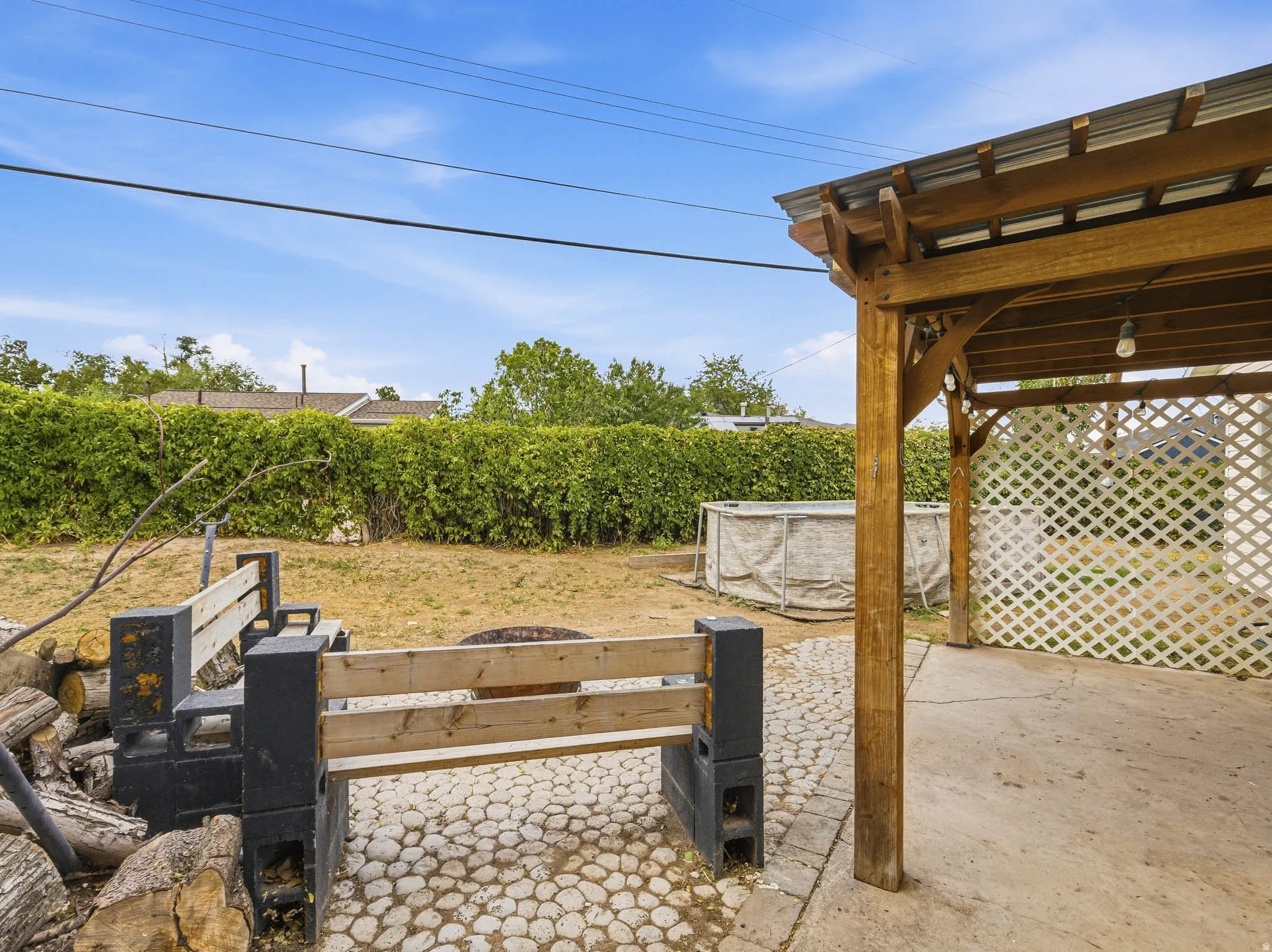 Outdoor patio with a wood pergola, concrete flooring, and an adjacent stone-paved area