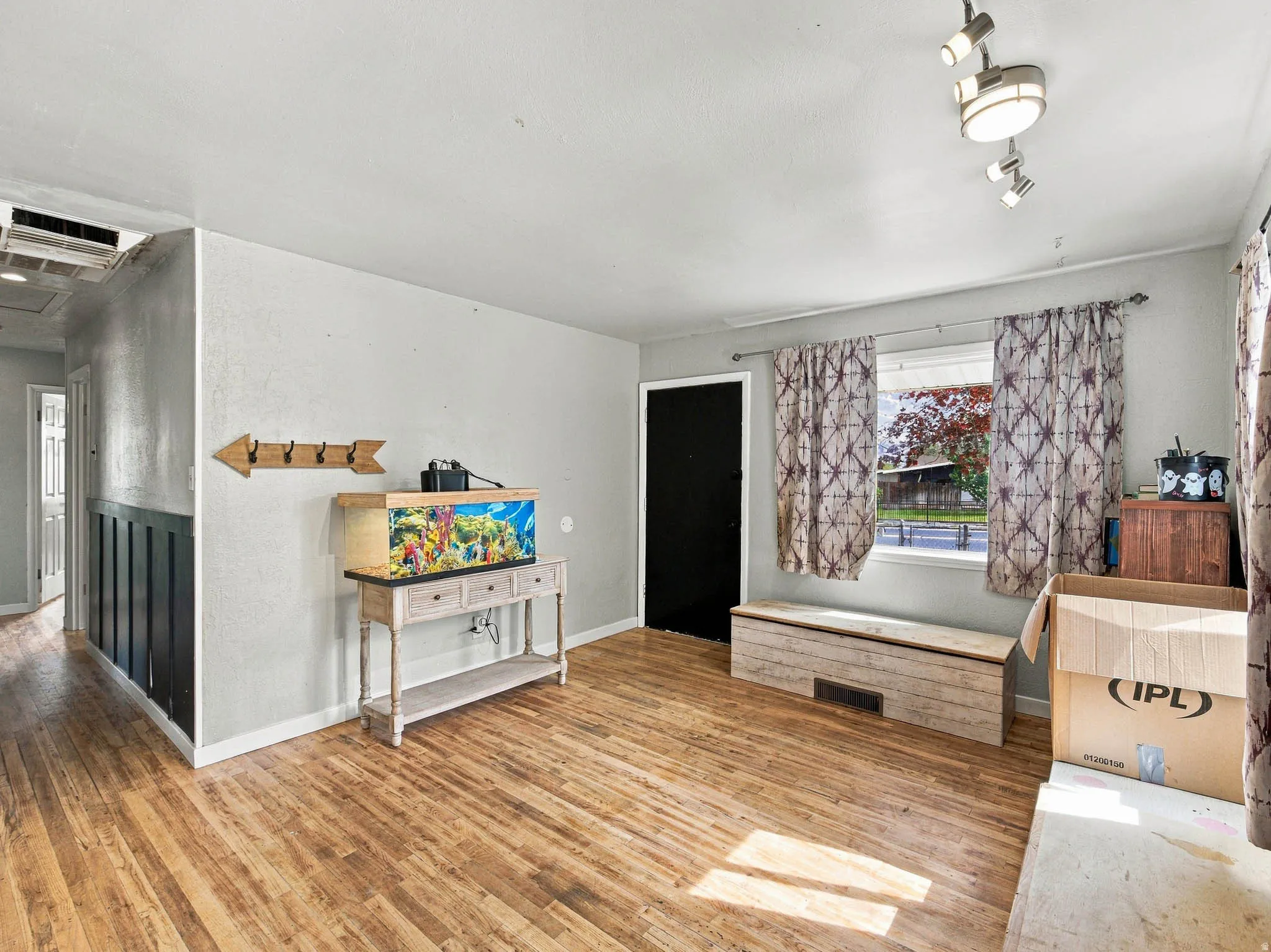 Wood-finish flooring, half-wall paneling, and a track lighting fixture are present