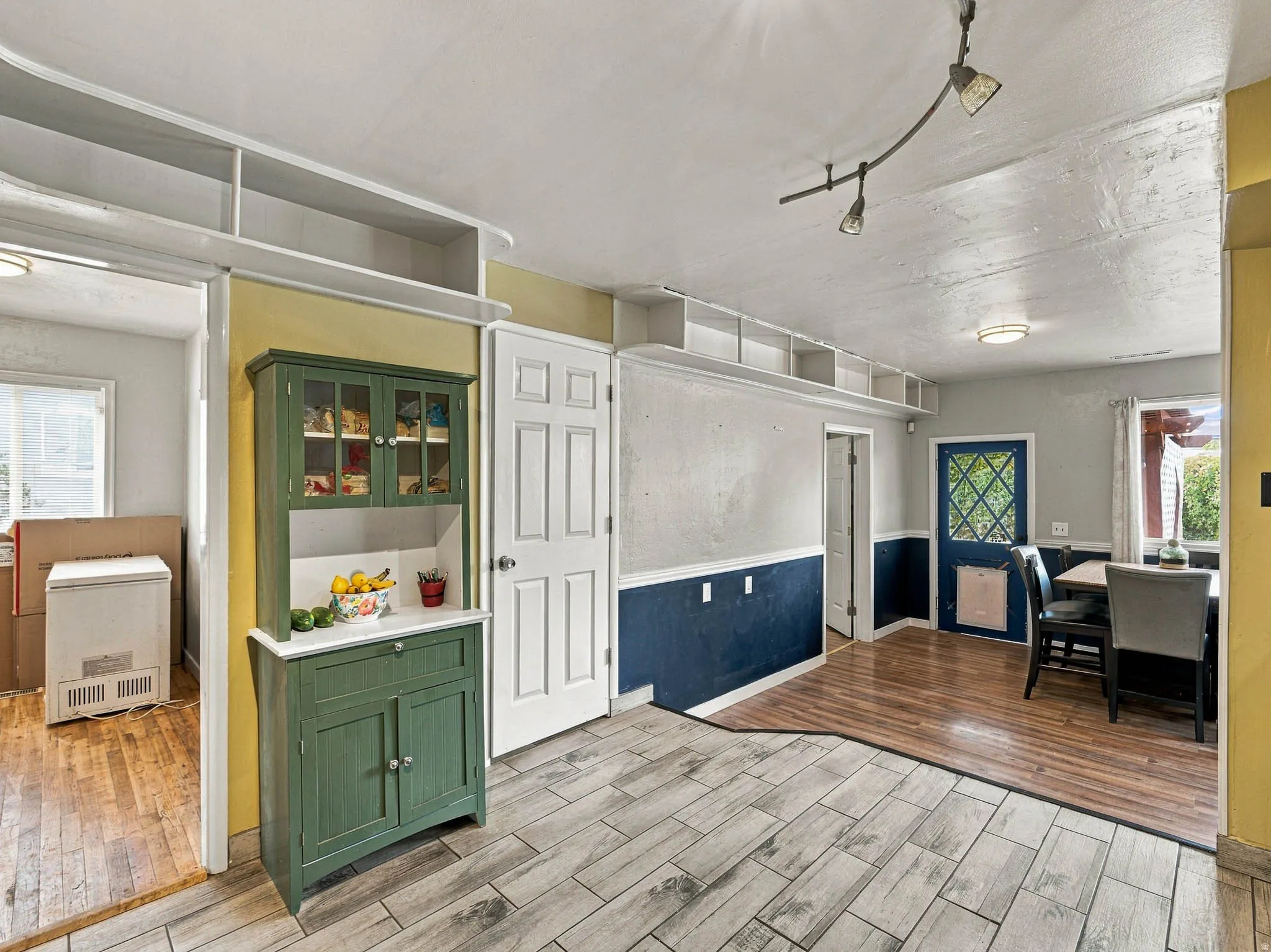 Contrasting flooring with wood-finish and light-toned tile, built-in shelving, two-toned wall treatment, and a paneled door