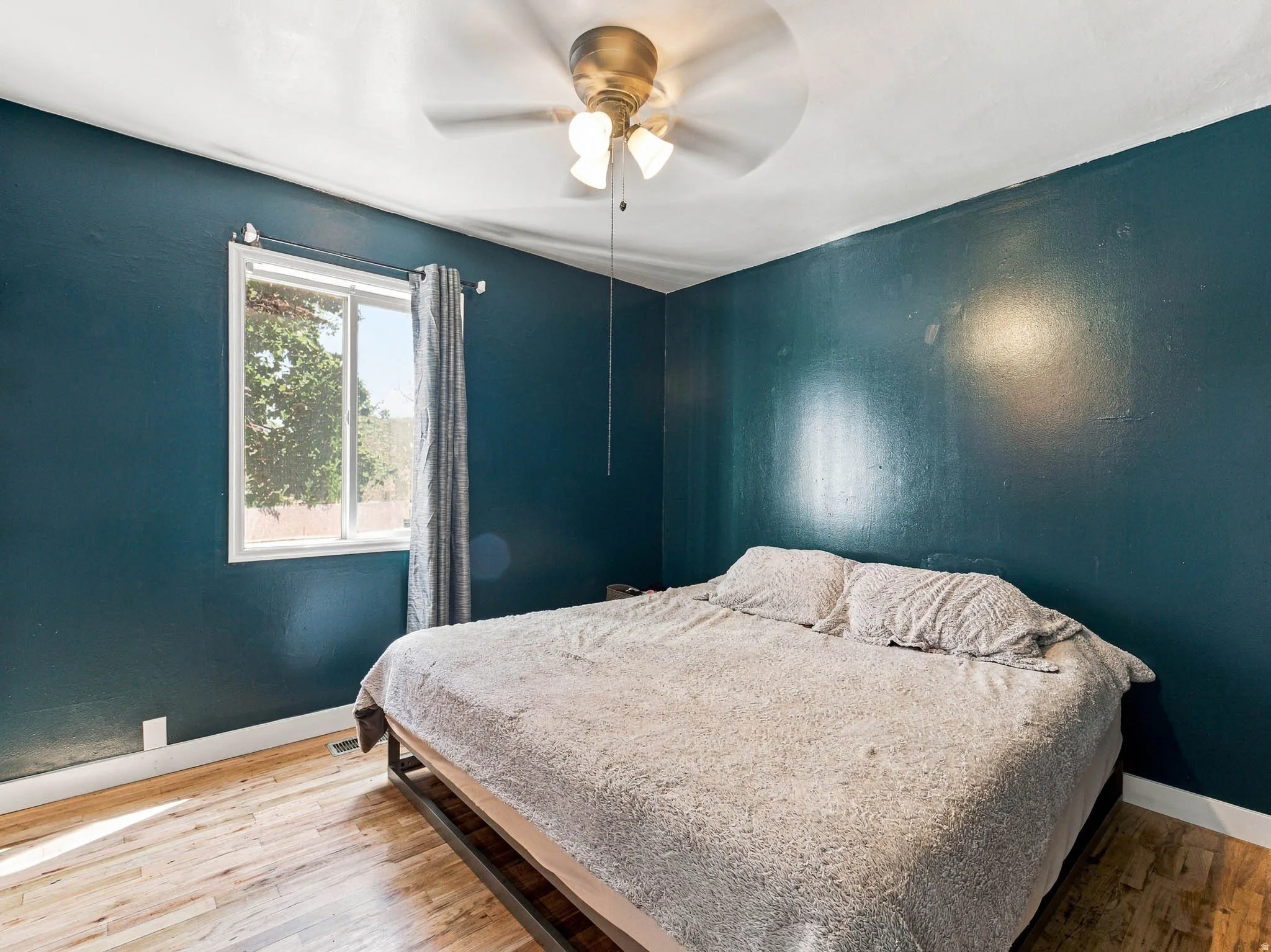 Hardwood-style flooring with a single window and a ceiling fan with integrated lighting