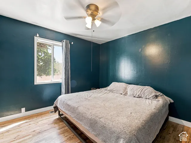 Hardwood-style flooring with a single window and a ceiling fan with integrated lighting