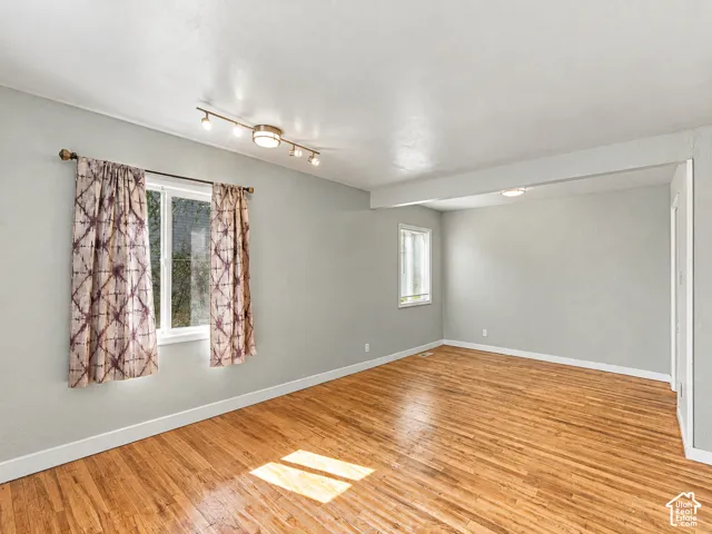 Interior space featuring wood-finish flooring, neutral wall tones, multi-bulb track lighting, and double-pane vinyl windows