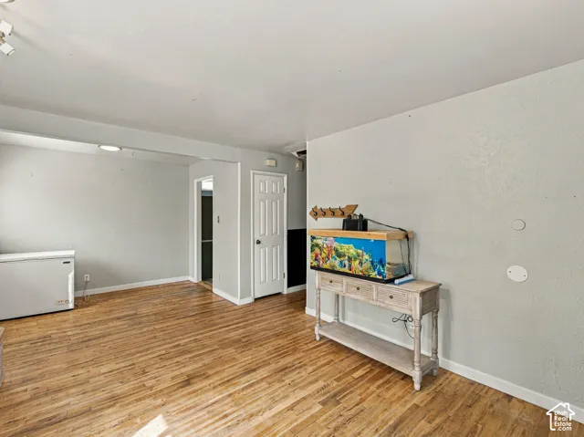 Wood-finish flooring with white trim, track lighting, and a paneled interior door