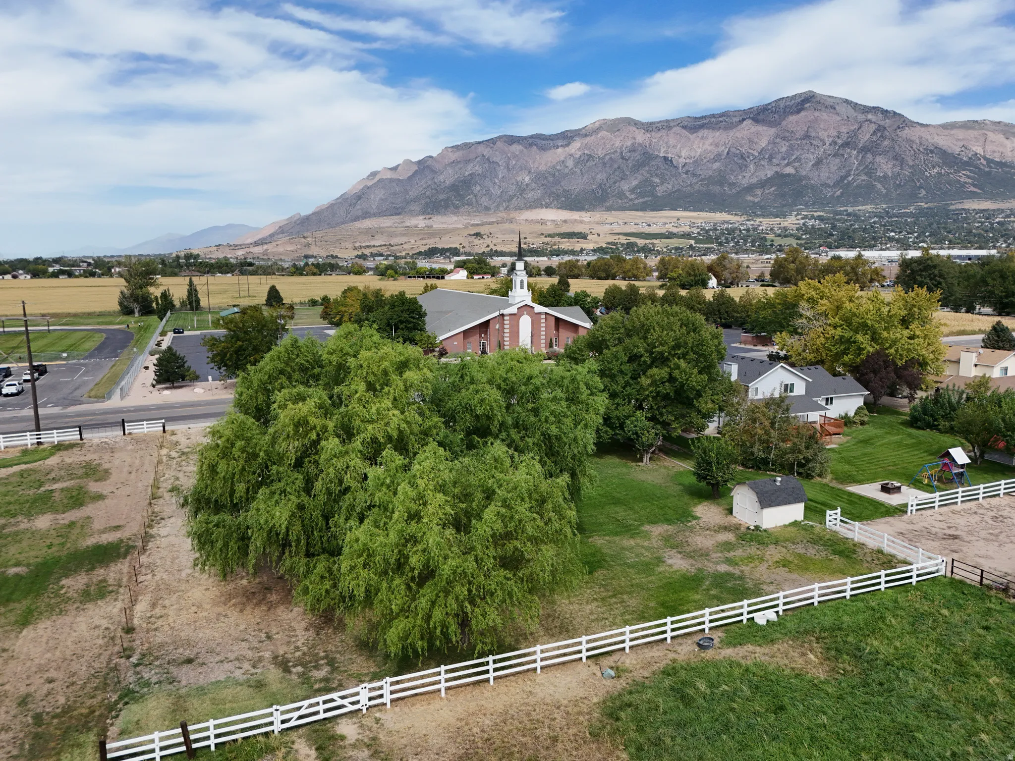 Expansive rural setting with mountain backdrop, residential structures, and natural landscaping