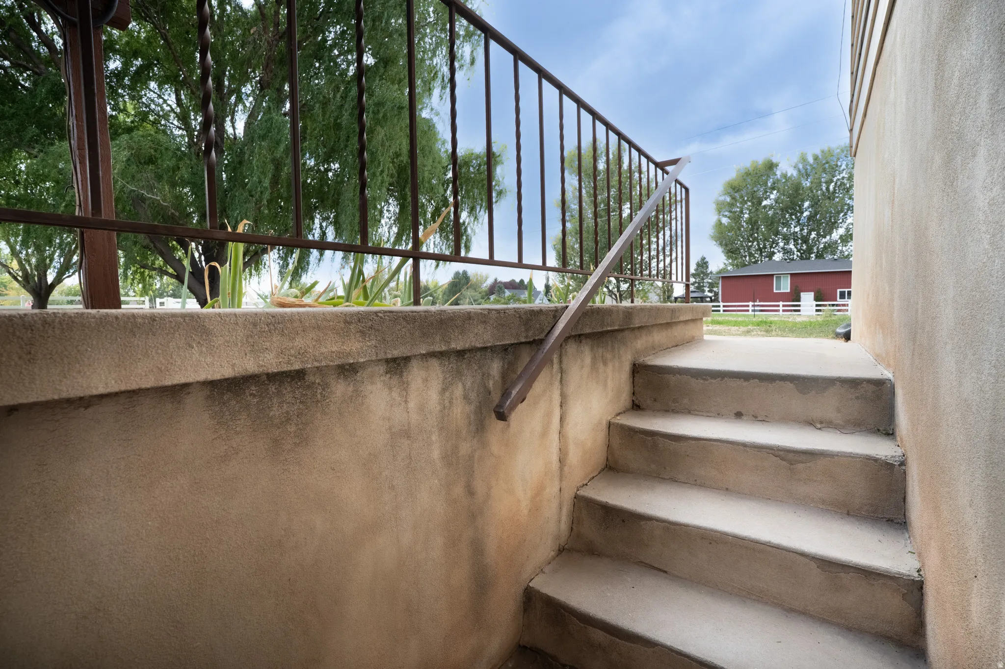 Concrete steps with a metal handrail and decorative wrought iron railing on walkout basement.