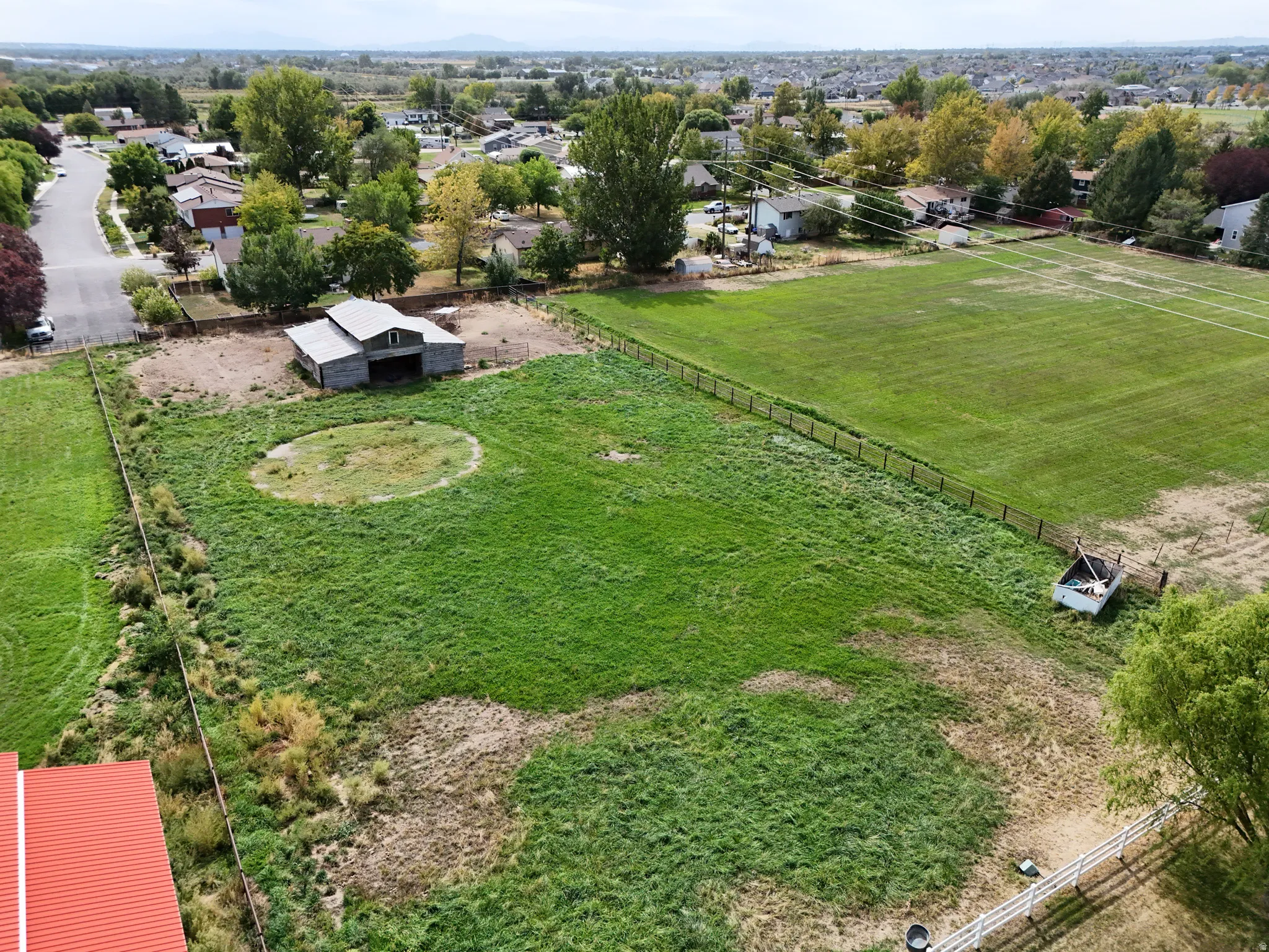 Expansive green space featuring a large barn, perimeter fencing, and mature trees. Expansive extra yard.