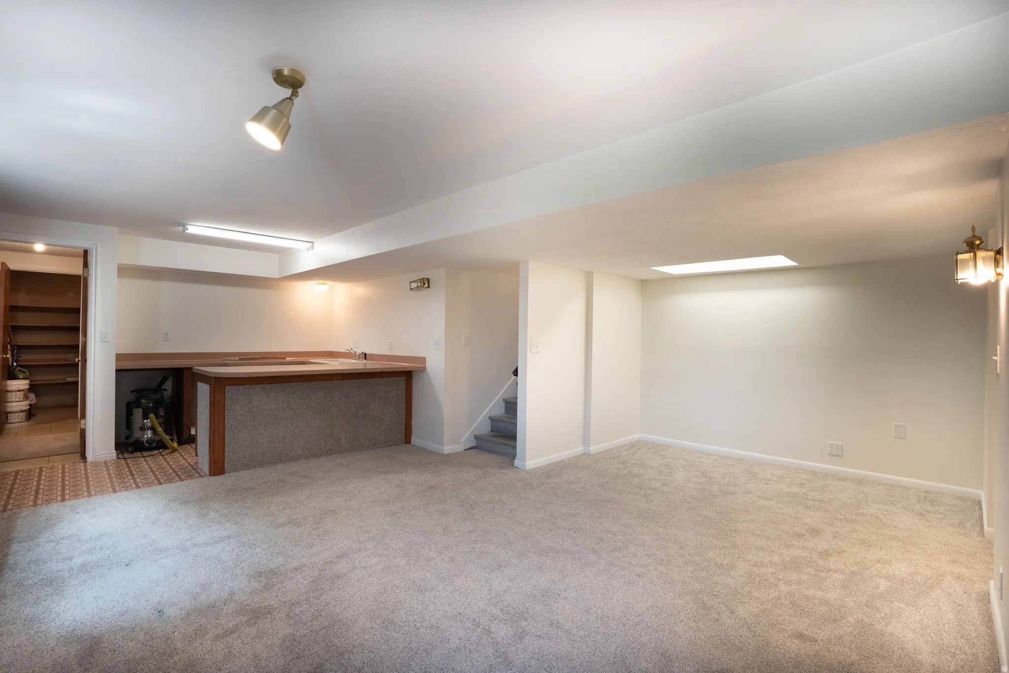 Kitchen area in basement with counters, sink, and plumbed for stove.