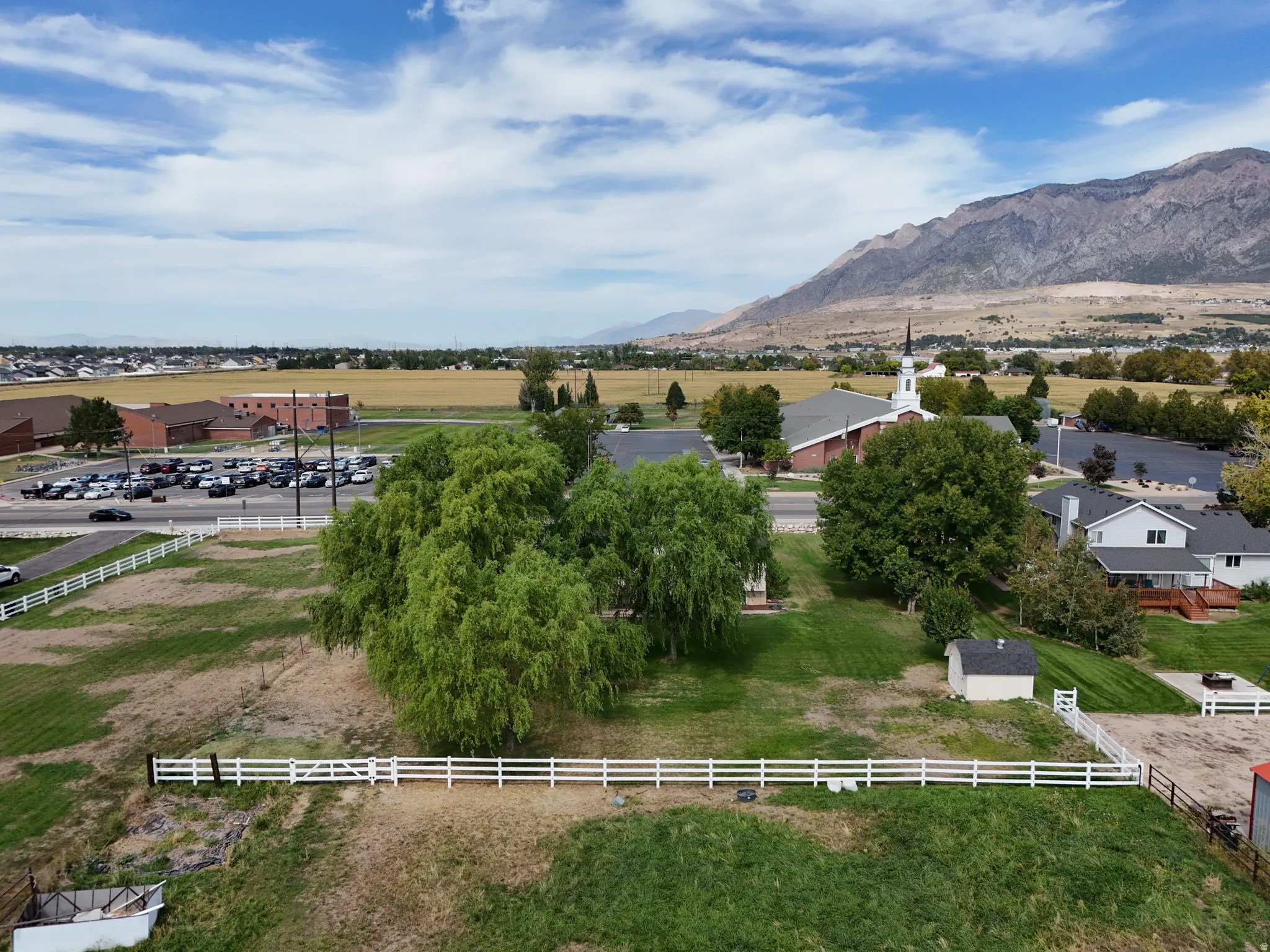Expansive property with a white fence, mature trees, and a detached shed with mountain views