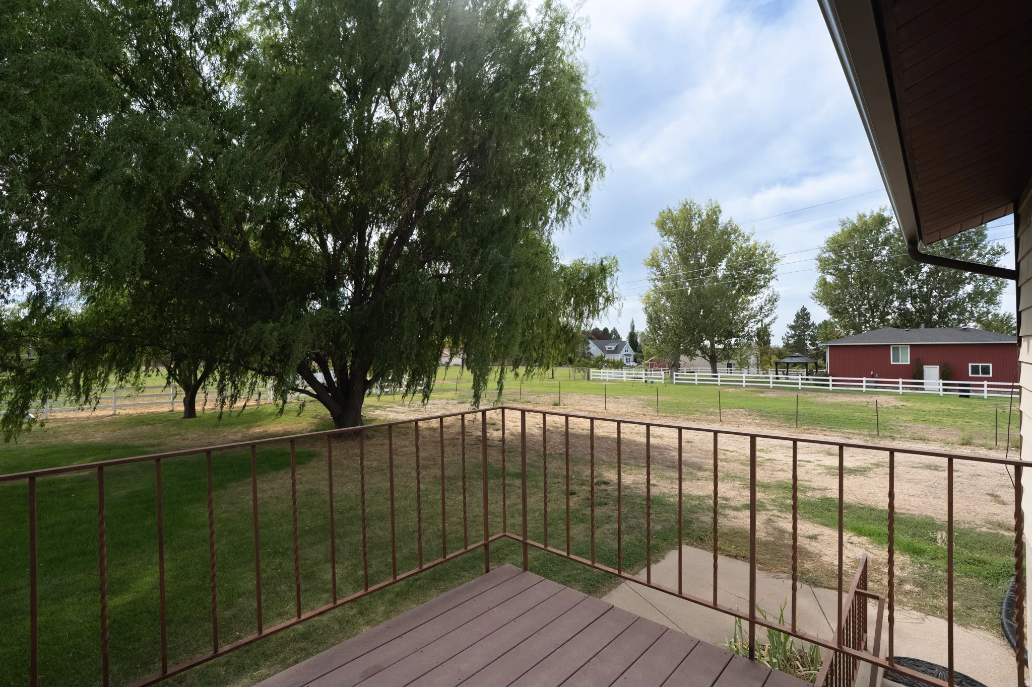 Trex-deck with wood-finish surface and metal railing overlooking a spacious yard with mature trees