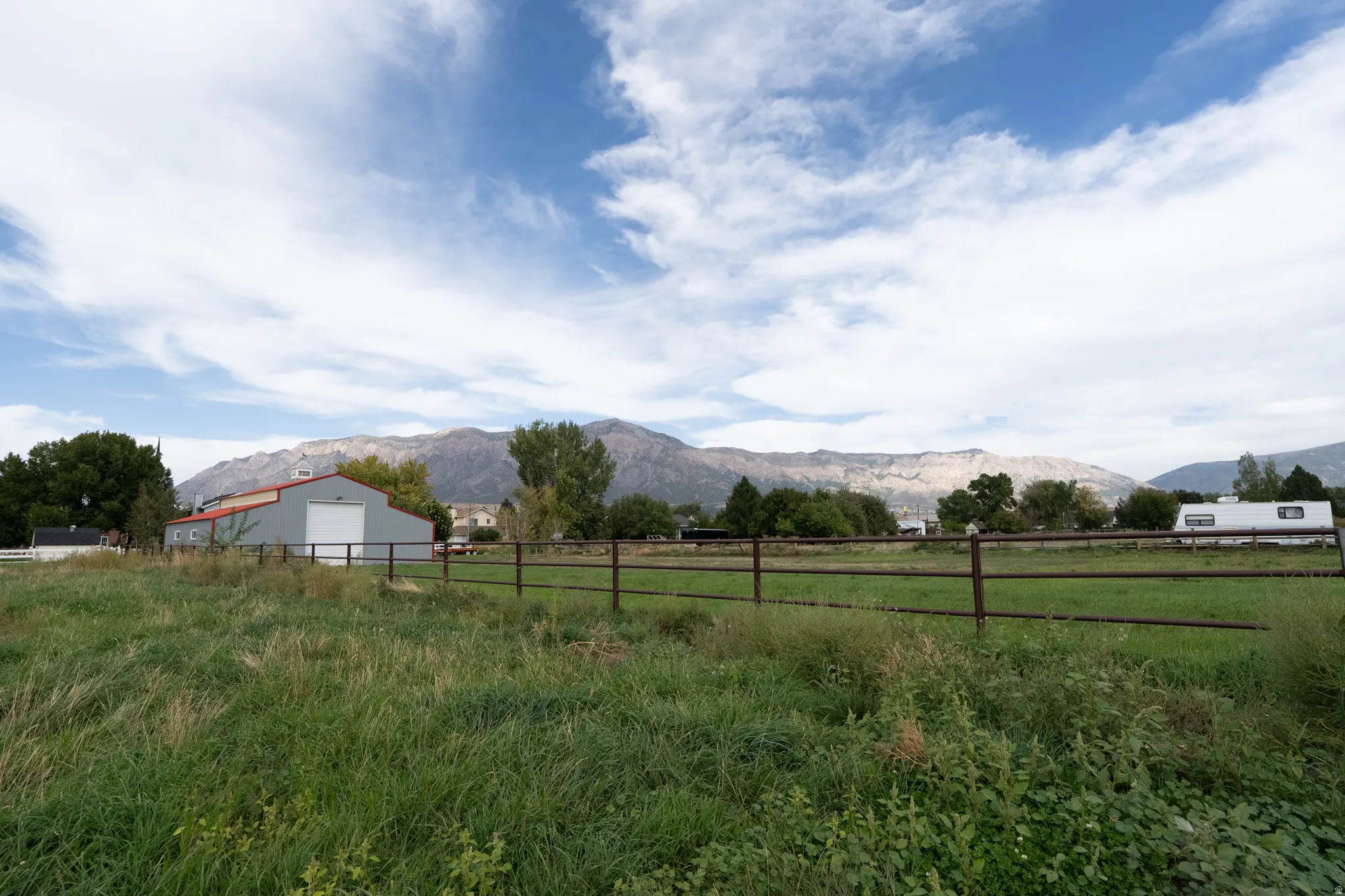 Expansive green field with a metal fence and mountainous backdrop