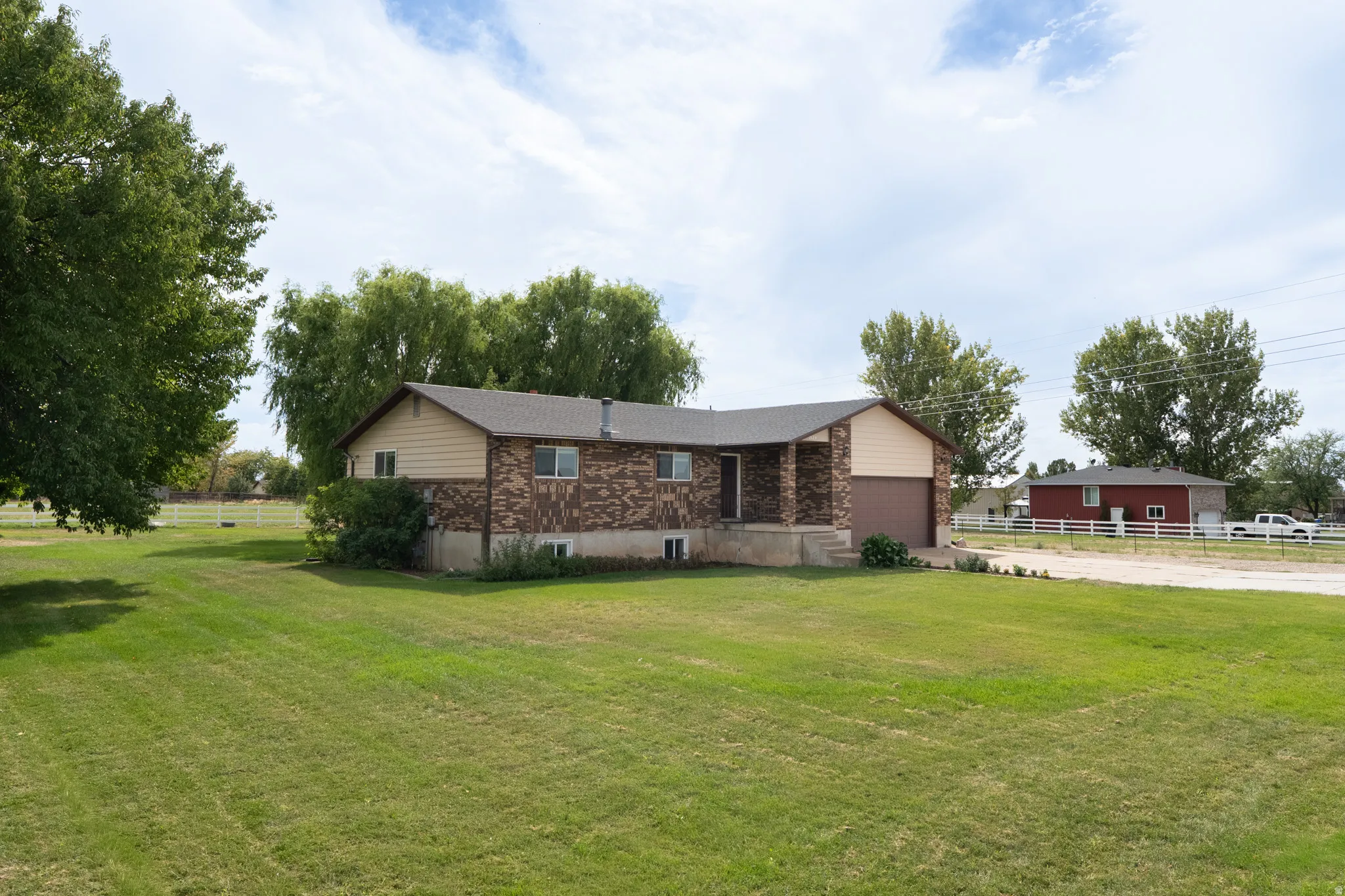 Spacious lawn with mature trees, a brick and siding exterior, an attached garage, and a covered front entry