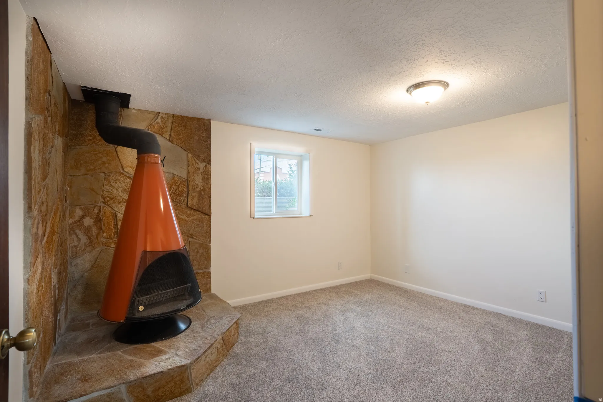 Stone accent wall featuring a freestanding fireplace with an orange finish