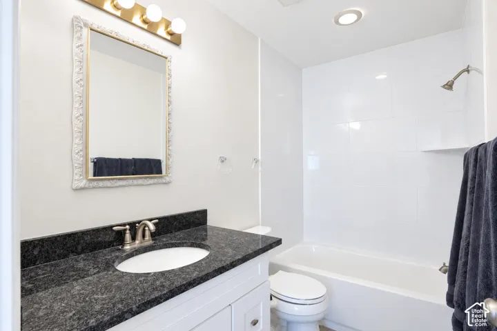 White vanity with a dark speckled countertop, undermount sink, and brushed nickel faucet and brand new shower tile, fixtures