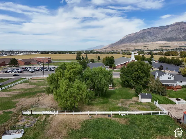 Expansive property with a white fence, mature trees, and a detached shed with mountain views