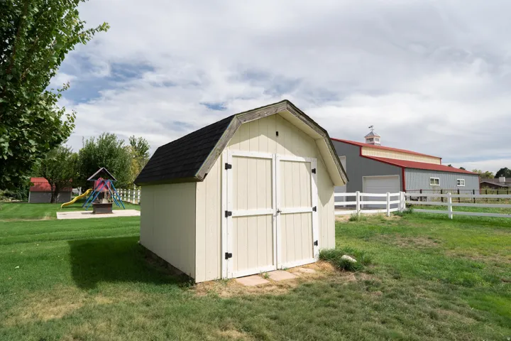 Exterior shed with double doors and black shingle roof