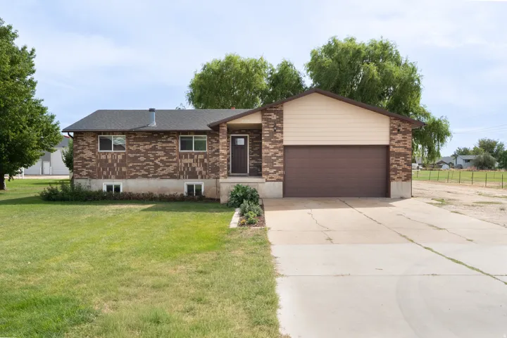 Brick and siding exterior with an attached two-car garage, mature landscaping, and an expansive concrete driveway with RV parking.