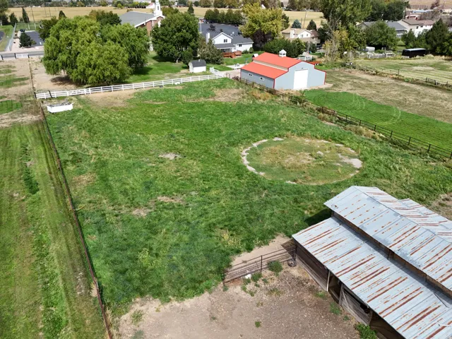 Expansive grassy lot featuring two outbuildings and perimeter fencing