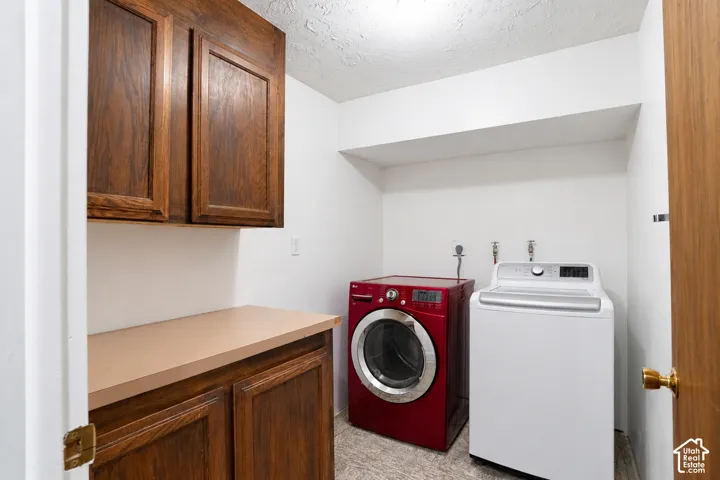 Laundry area with wood-finish cabinetry, a light-toned countertop, and an overhead shelf