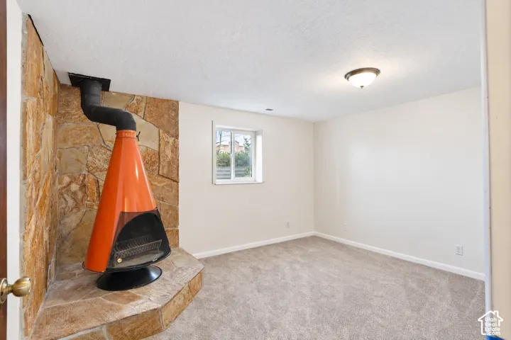 Freestanding fireplace with an orange finish, stone-clad accent wall, and a raised stone hearth in Bedroom 5
