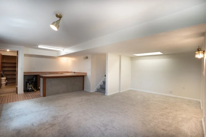 Kitchen area in basement with counters, sink, and plumbed for stove.