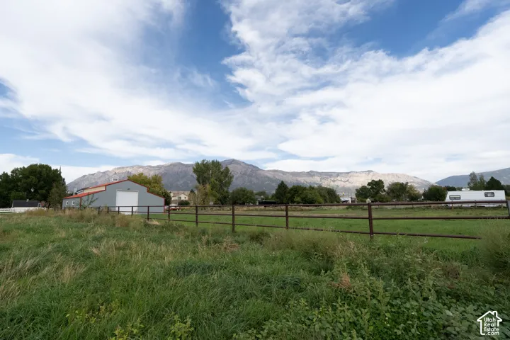 Expansive green field with a metal fence and mountainous backdrop