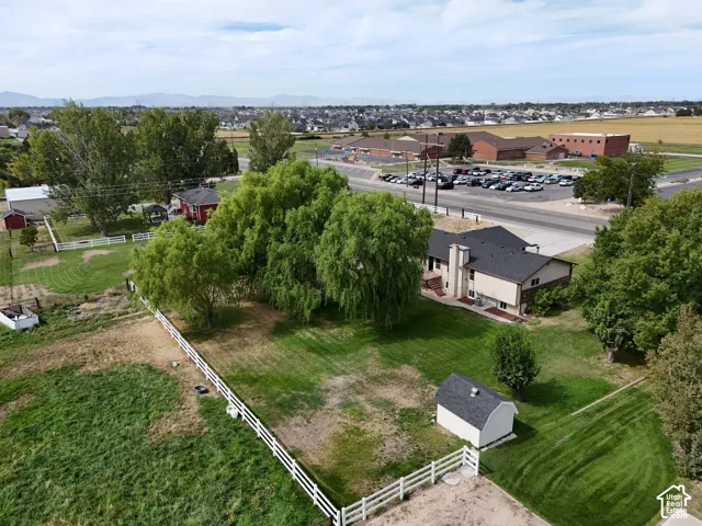 Expansive property featuring a white picket fence, a large green lawn, mature trees, and an accessory shed