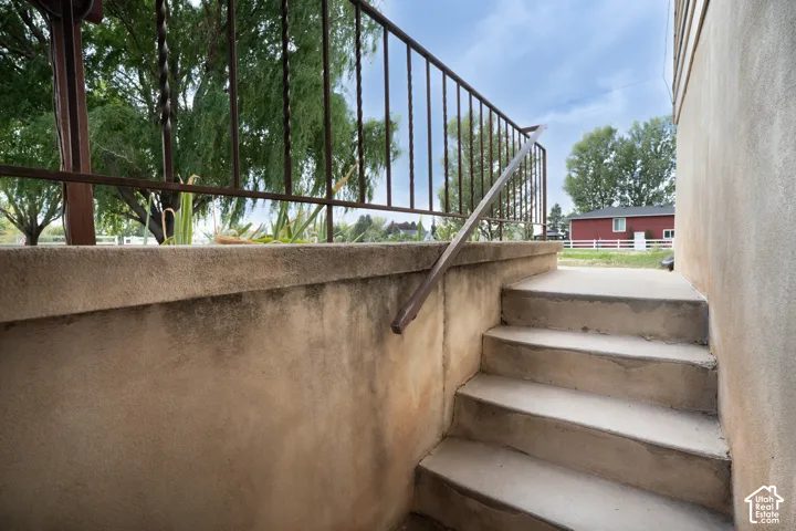 Concrete steps with a metal handrail and decorative wrought iron railing on walkout basement.