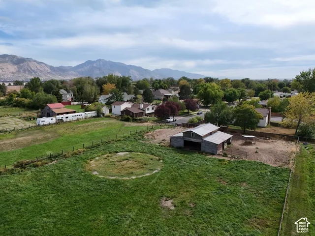 Expansive grounds featuring a large grassy area, a barn structure with a metal roof, and distant mountain scenery with back entrance from neighborhood