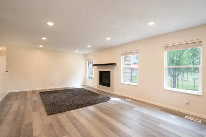 Spacious living room with new flooring, new mantle, new paint, and gas fireplace.