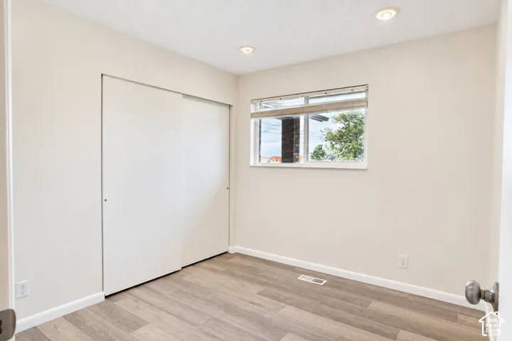Bedroom 2 Recessed ceiling lighting, wood-finish flooring, sliding closet doors, and a window with blinds