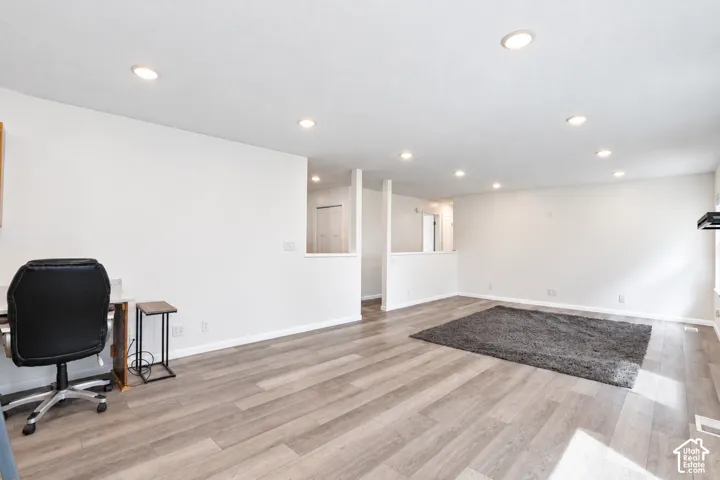 Recessed lighting illuminating the expansive living area with wood-finish flooring