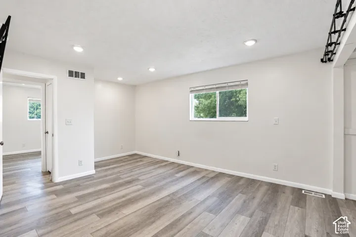 Light-toned wood-finish flooring, recessed lighting, and a white interior paint scheme