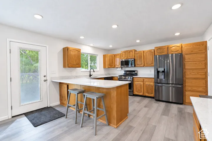 Kitchen featuring wood-finish cabinetry, light-toned countertops, and stainless steel appliances