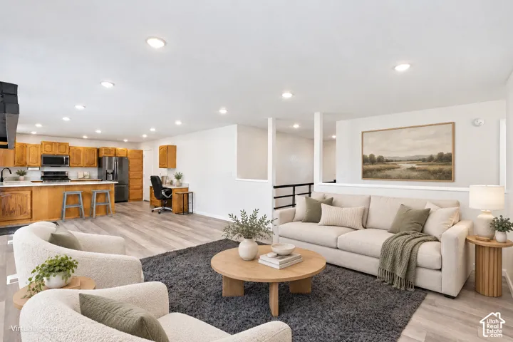 Recessed lighting, wood-finish flooring, half-wall with railing, kitchen featuring wood cabinetry, and stainless steel appliances
