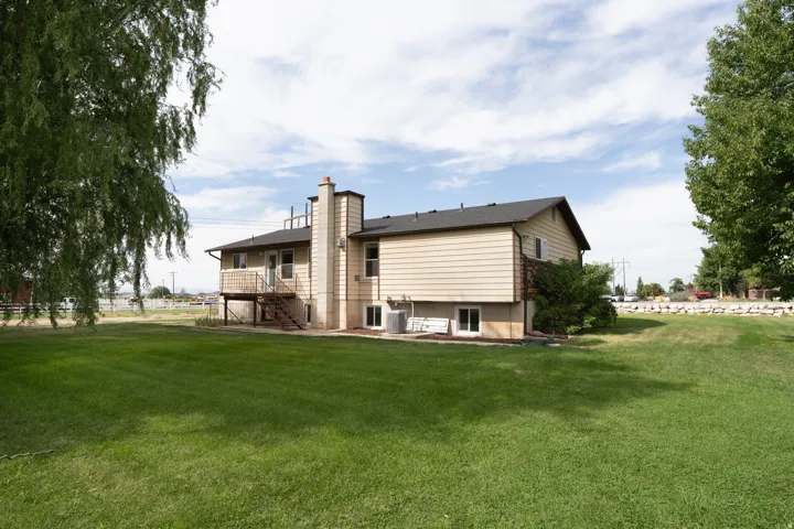 Back of the house, expansive green lawn surrounds the property featuring a second-story deck with exterior stairs, a chimney.
