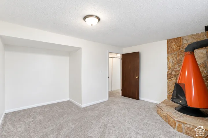 Bedroom 5 Wall-to-wall carpeting, built-in wall niche, dark wood-finish door, stone-clad fireplace surround, and a freestanding orange fireplace