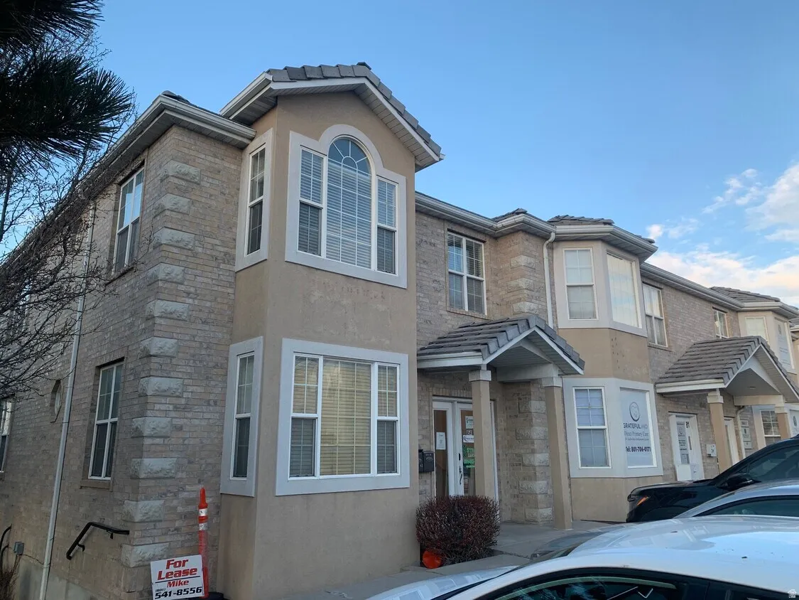 Stucco and stone veneer exterior with multiple bay windows and arched window accents
