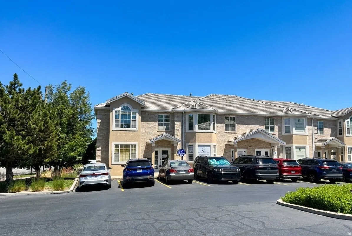 Multi-level commercial building featuring a stone and stucco exterior, arched entryway porticos, and a dedicated parking lot
