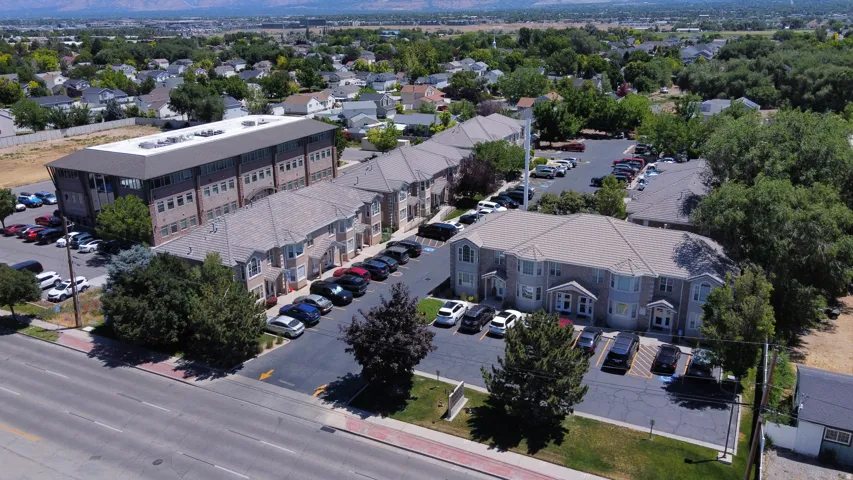 Expansive property featuring multiple multi-story buildings, paved parking areas, mature landscaping, and mountainous surroundings