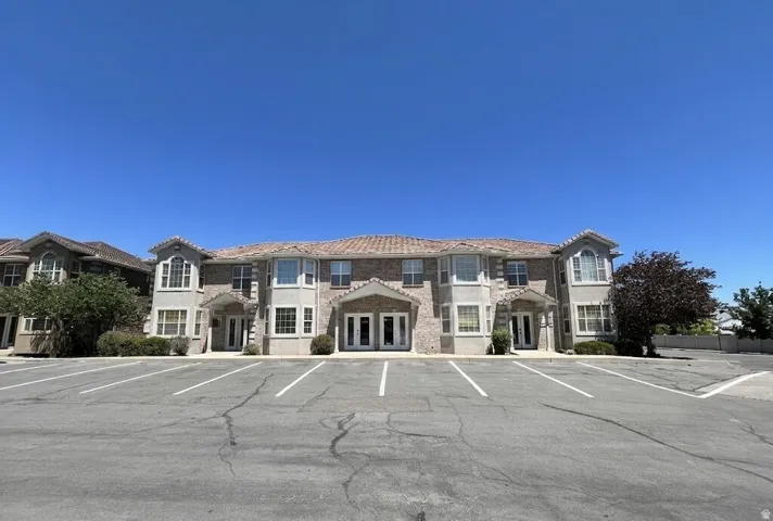 Building exterior featuring a tile roof, bay windows, brick accents, and a paved parking area